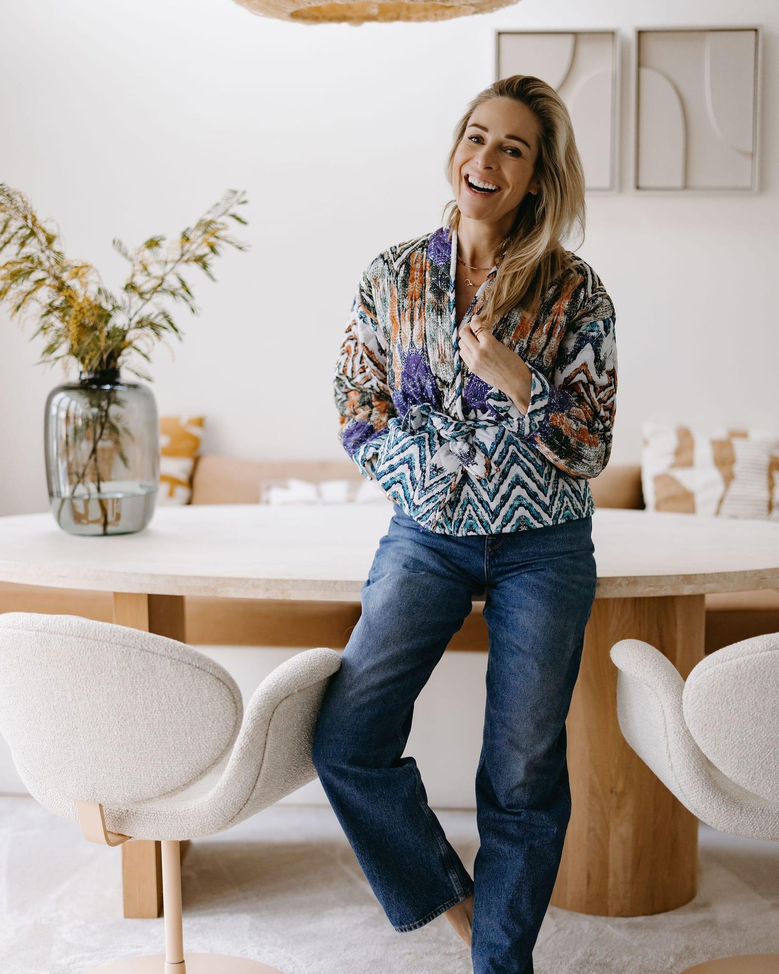 Virginie Versteegh in een kleurrijke blouse, lachend bij een lichte eettafel