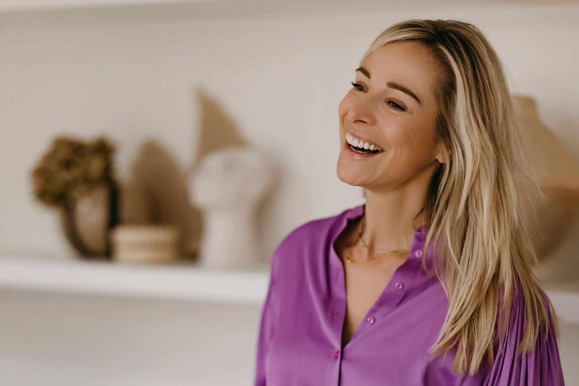 Virginie Versteegh in een paarse blouse, lachend en opzij kijkend