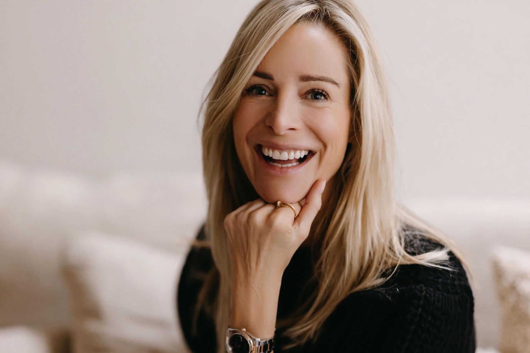 Virginie Versteegh lachend op een bank, met haar kin op haar hand