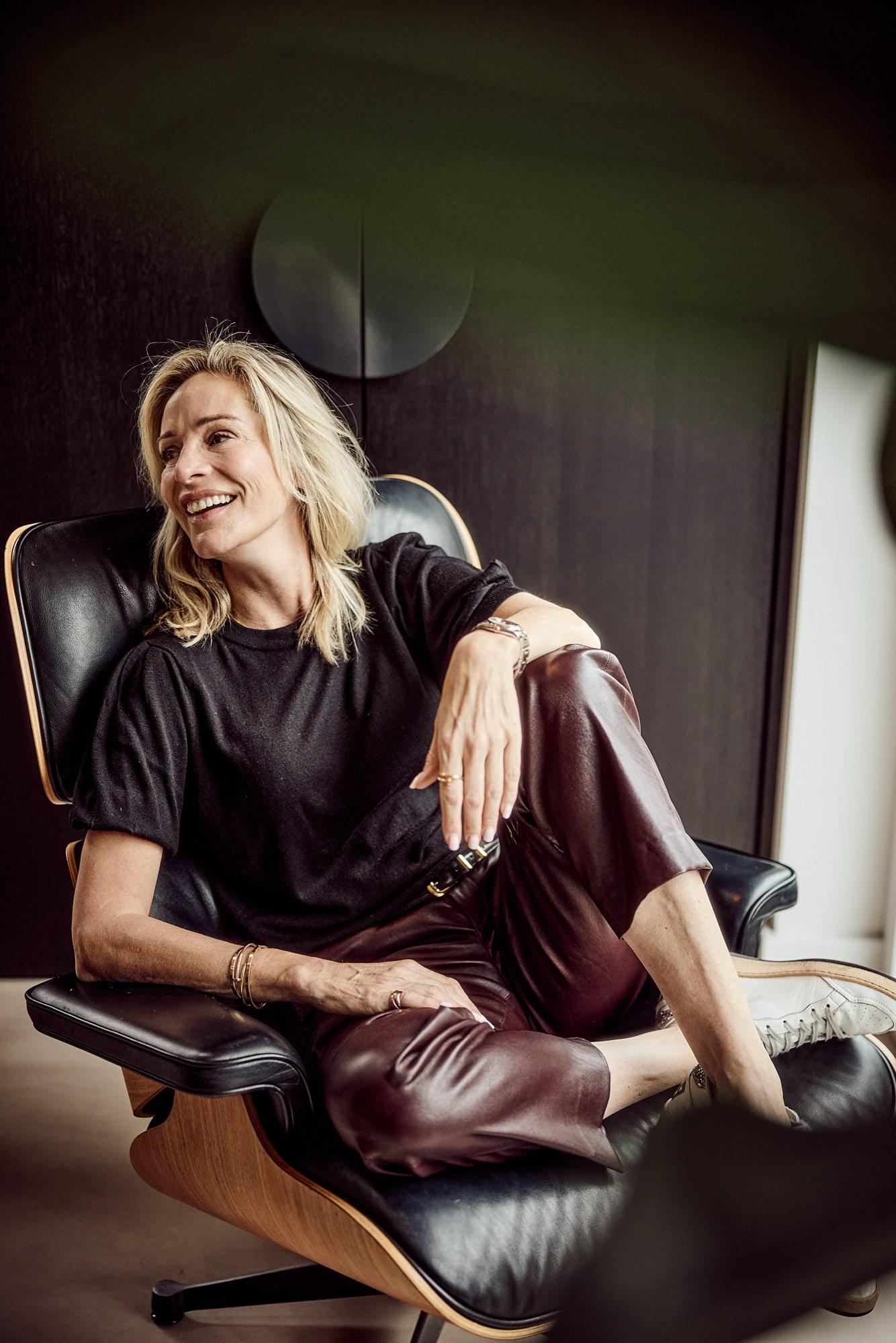 Virginie Versteegh lachend in een zwarte leren fauteuil