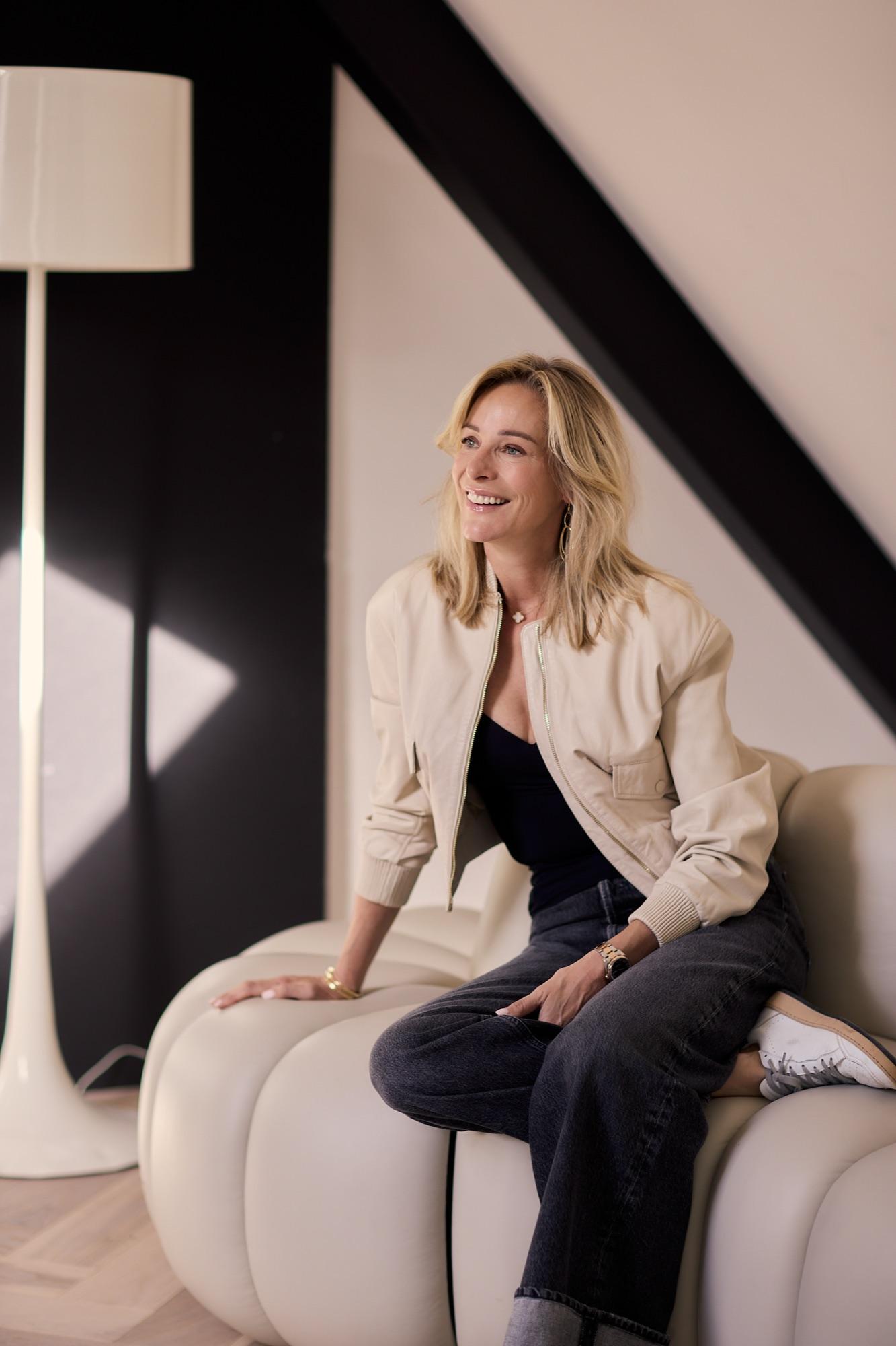 Virginie Versteegh in een beige jasje, ontspannen zittend op een bank