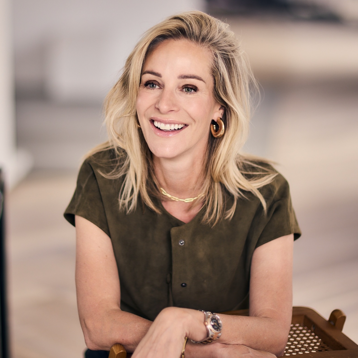 Virginie Versteegh in een groene blouse, lachend op een stoel