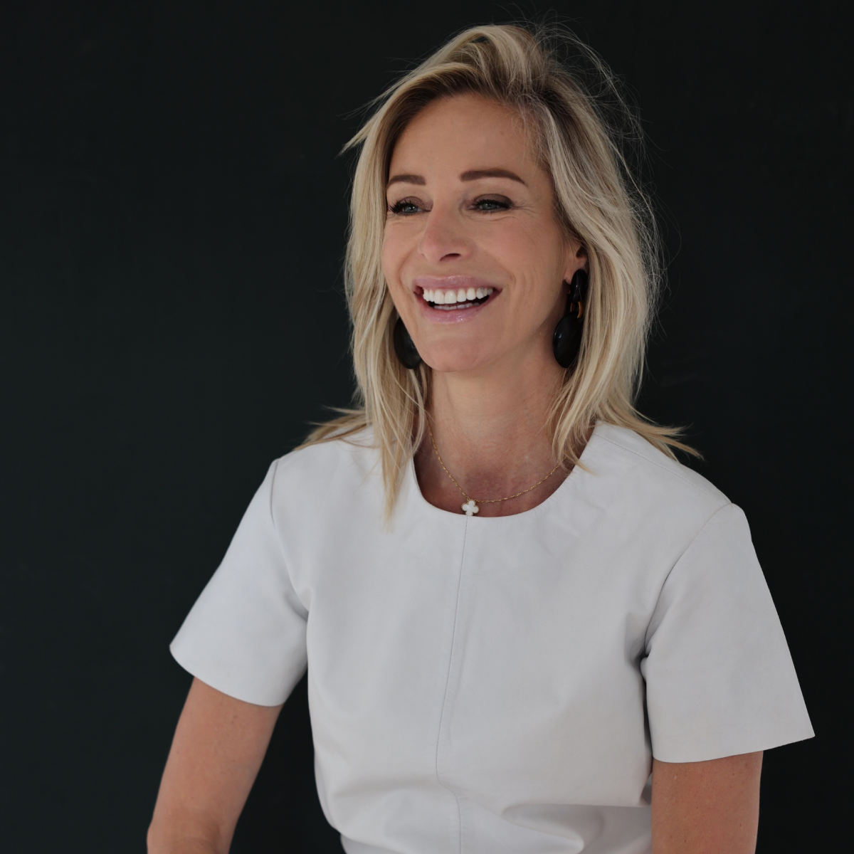 Virginie Versteegh, lachend in een wit shirt tegen een donkere achtergrond