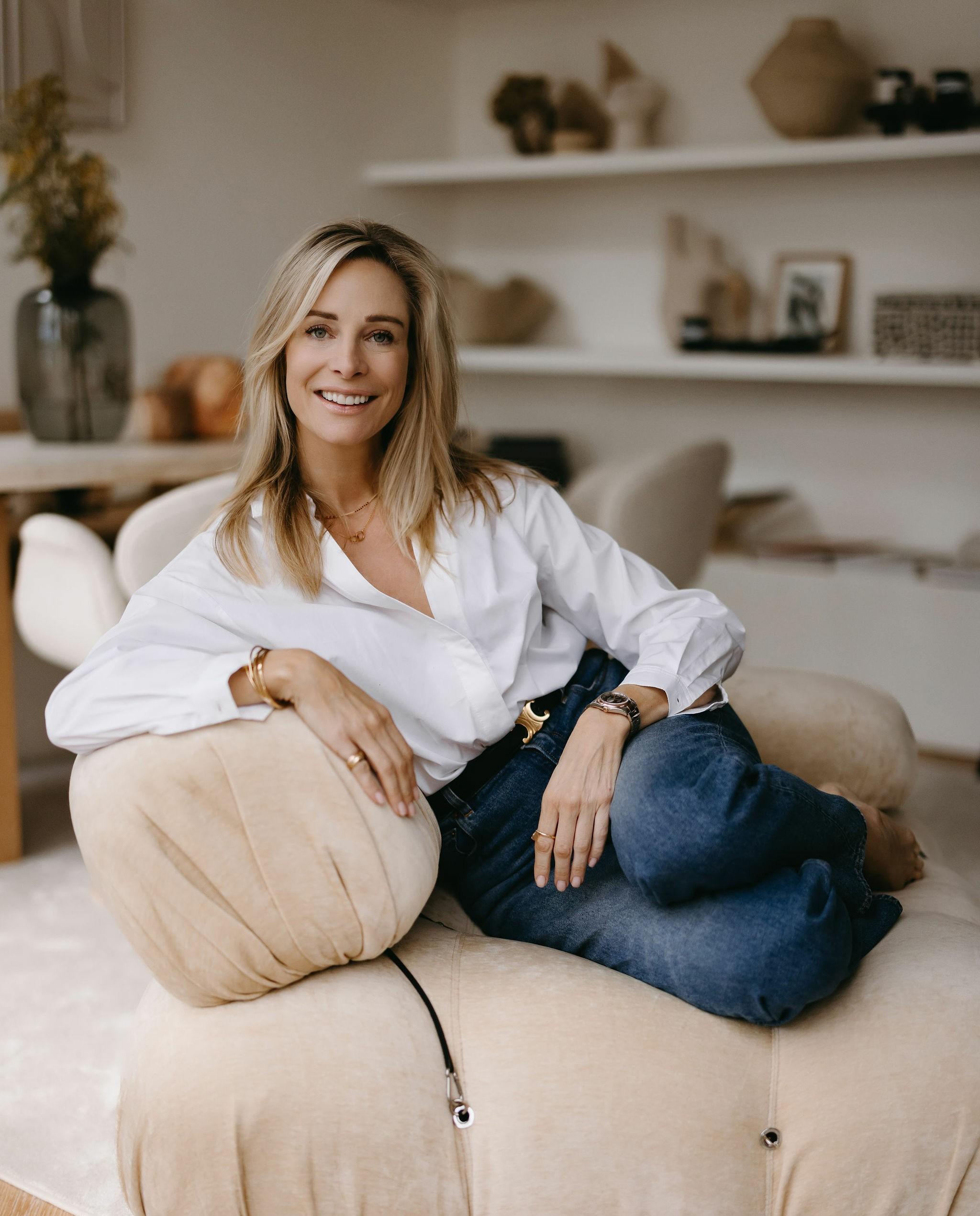Virginie Versteegh in een witte blouse, ontspannen zittend op een bank