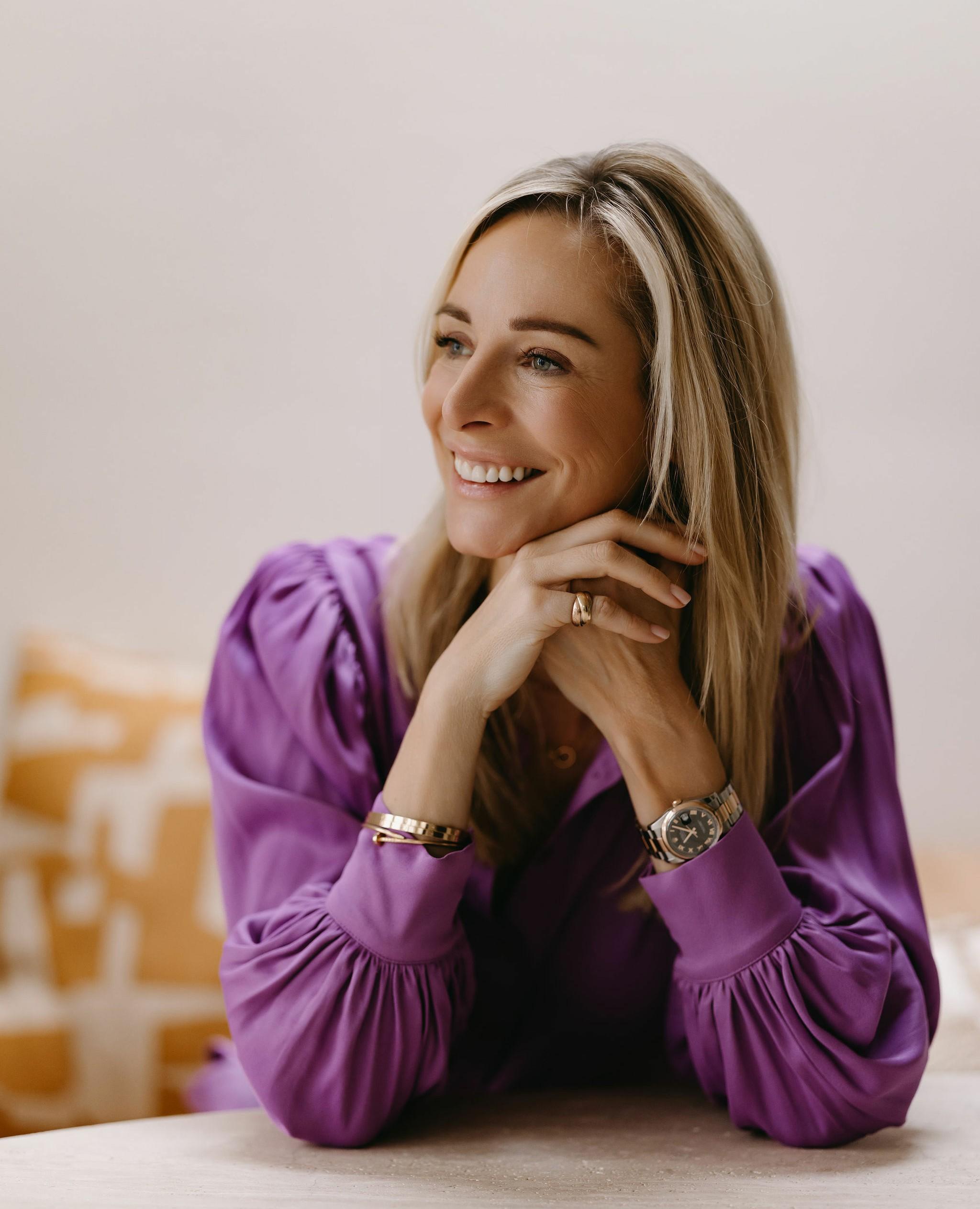 Virginie Versteegh in een paarse blouse, lachend met haar kin op haar handen