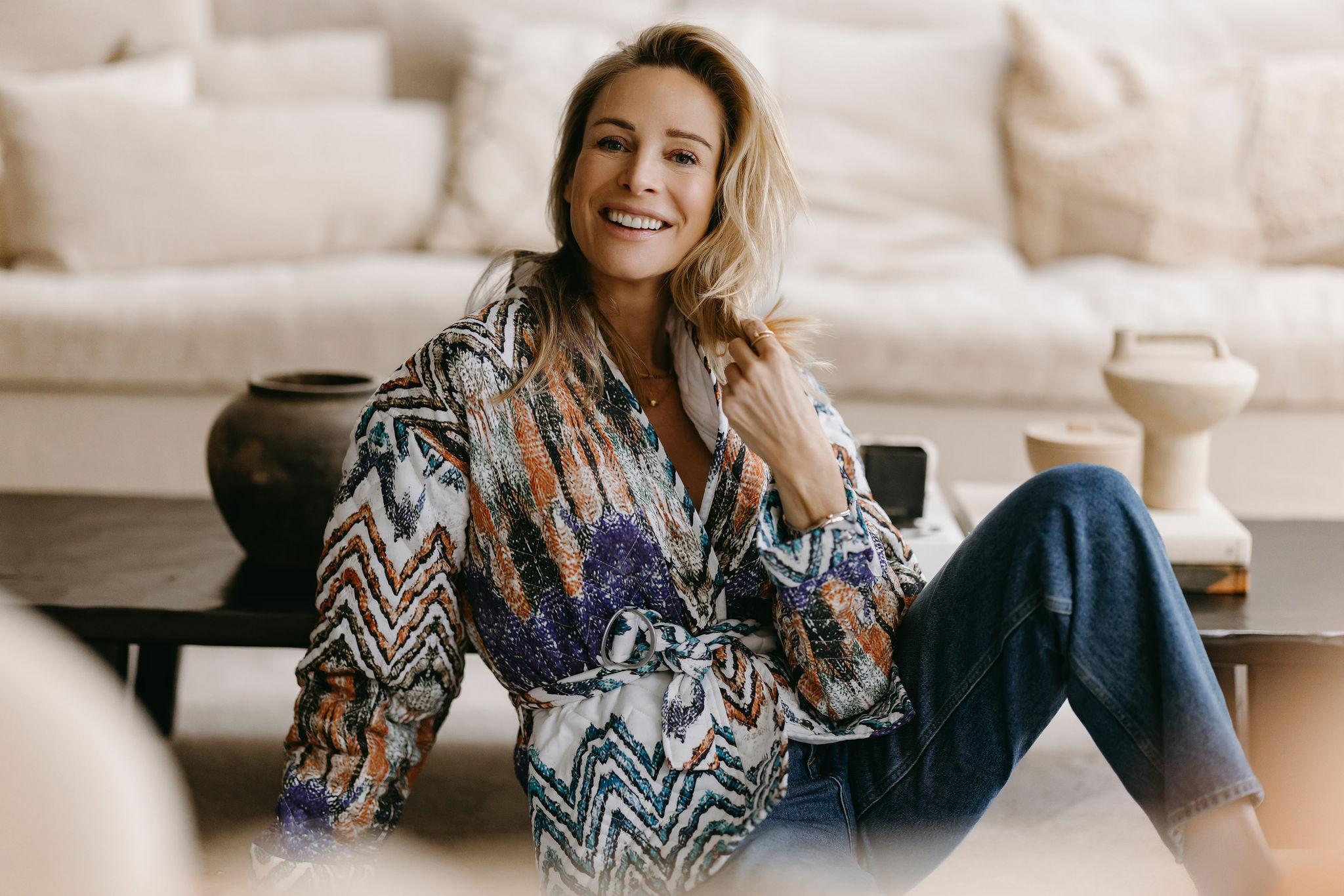 Virginie Versteegh in een kleurrijke blouse, zittend voor een lichte bank